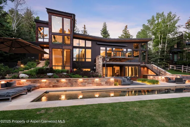 a view of swimming pool with seating area and trees in the background