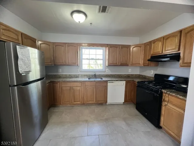 a kitchen with granite countertop a refrigerator stove top oven a sink and dishwasher