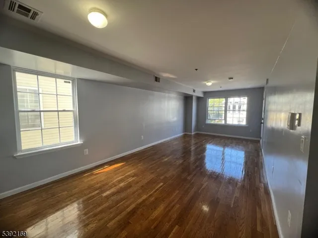a view of empty room with wooden floor and fan