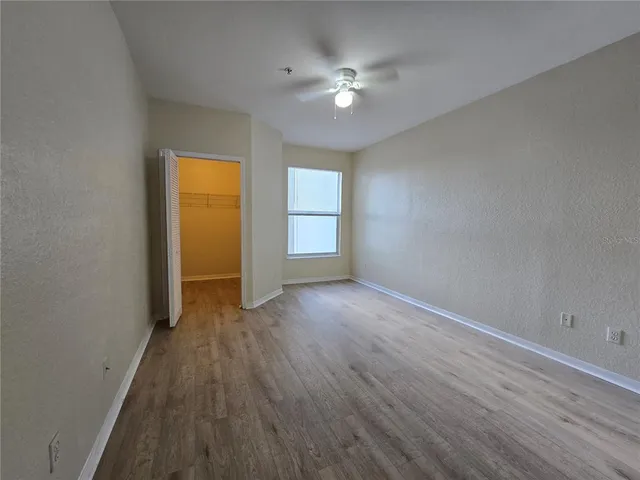 a view of an empty room with a ceiling fan and window