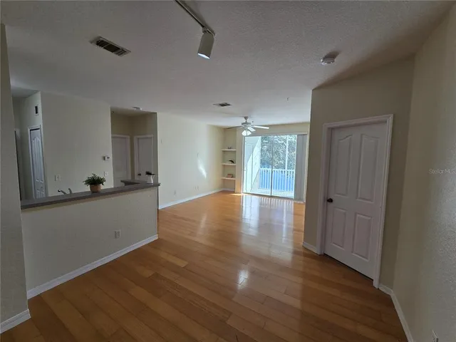 a view of an empty room with window and wooden floor