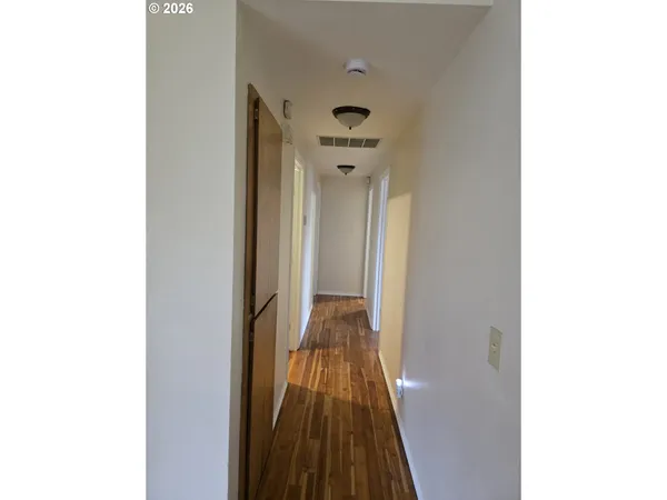 a view of a hallway with wooden floor and a bathroom