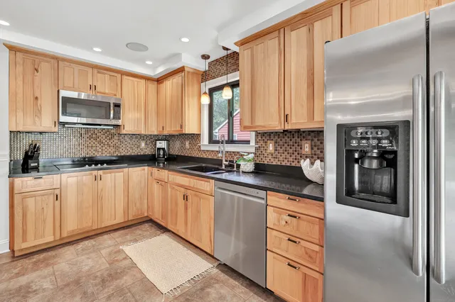 a kitchen with stainless steel appliances granite countertop a stove a sink and a refrigerator
