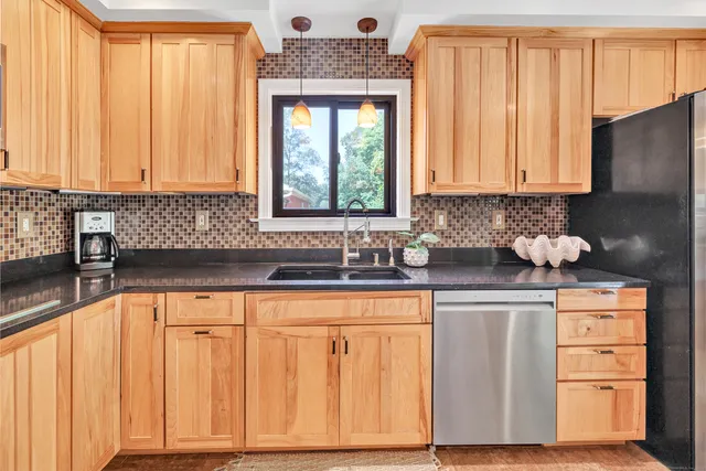 a kitchen with stainless steel appliances wooden cabinets a sink and a large window