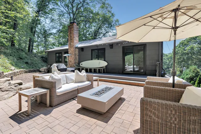 a view of a patio with couches table and chairs under an umbrella