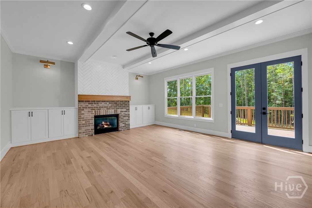 2476 St Martin Way Monroe, GA 30656 - Photo 9 of 75 Spacious family room featuring light wood-finish flooring, a brick gas log fireplace with a wood mantel, built-in cabinetry, recessed lighting, and a ceiling fan