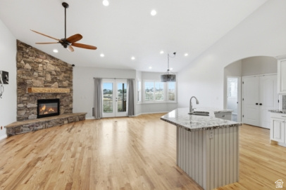 722 West Webb Circle, Unit 2 Draper, UT 84020 - Photo 2 of 39 Vaulted ceilings with recessed lighting, stone-clad fireplace with wood mantel, light wood-finish flooring, white double French doors, and a kitchen island with a granite countertop
