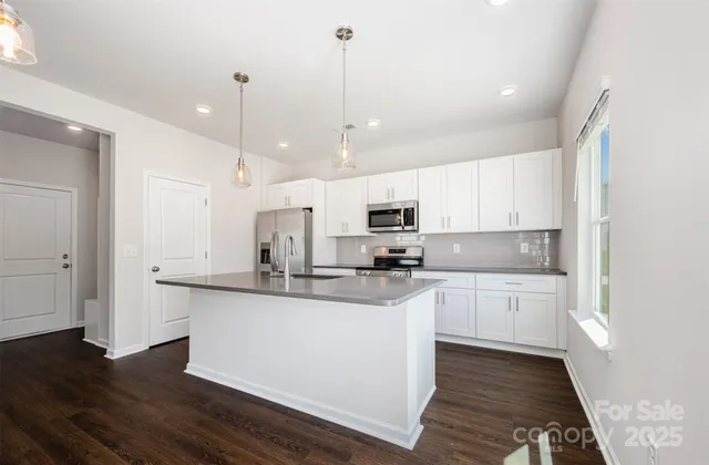 a kitchen with stainless steel appliances granite countertop a sink a stove and a wooden floors