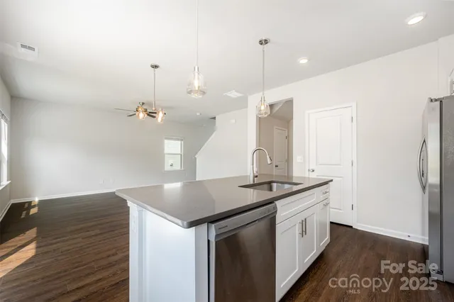 a kitchen with stainless steel appliances granite countertop a stove a sink and a wooden floor