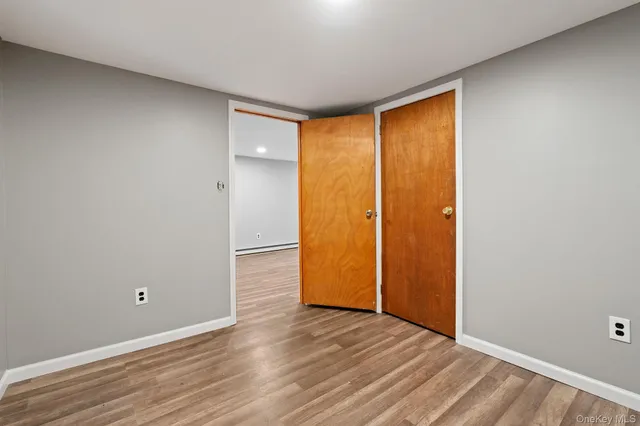 a view of an empty room with wooden floor and closet