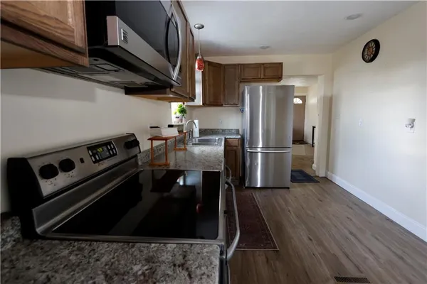 a kitchen with stainless steel appliances granite countertop a refrigerator a stove and a wooden floors