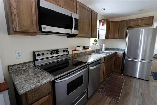a kitchen with stainless steel appliances granite countertop a stove microwave refrigerator and sink