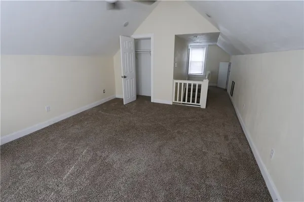 an empty room with windows and way to kitchen
