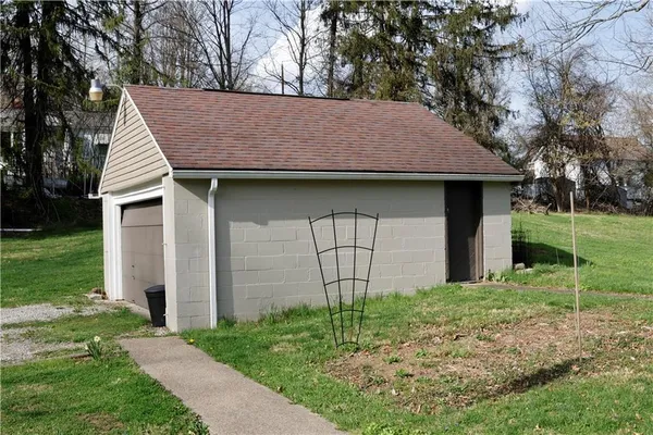 a backyard of a house with plants and large tree