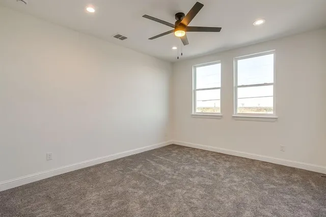 an empty room with windows and ceiling fan