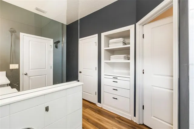 a bedroom with a bed and a walk in closet with wooden floor