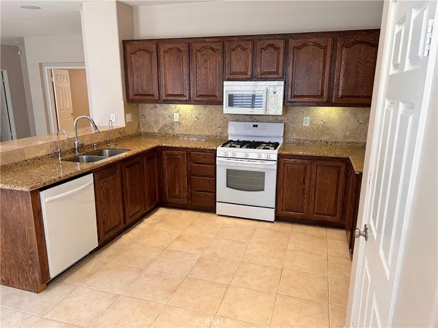 a kitchen with stainless steel appliances granite countertop a stove a sink dishwasher and a refrigerator