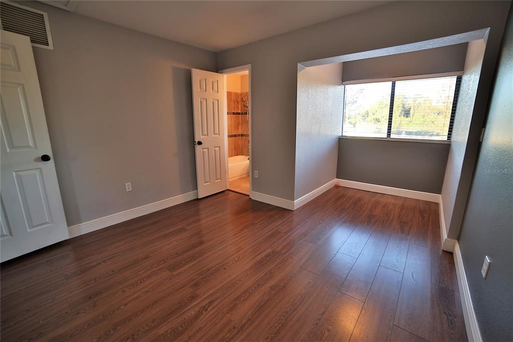 10260 Turkey Lake Road, Unit 149 Orlando, FL 32819 - Photo 14 of 18 an empty room with wooden floor and windows
