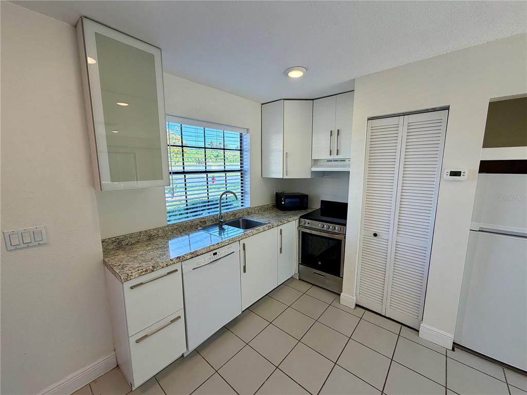 10260 Turkey Lake Road, Unit 149 Orlando, FL 32819 - Photo 7 of 18 a kitchen with white cabinets and white appliances