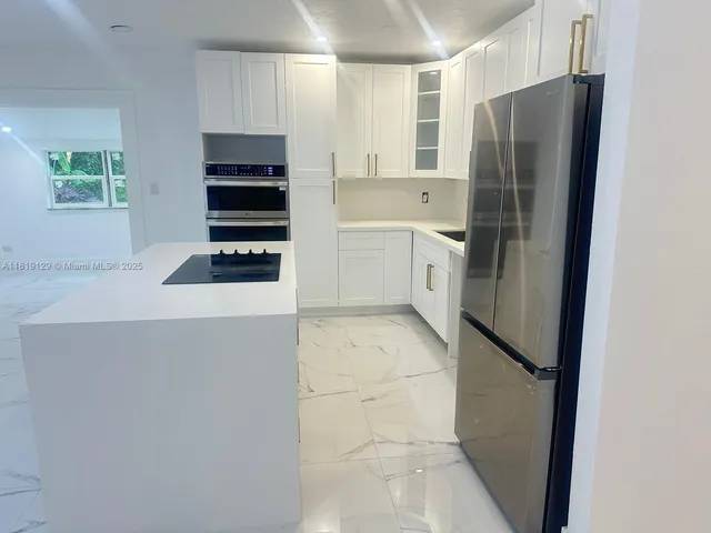 a kitchen with a refrigerator and white cabinets