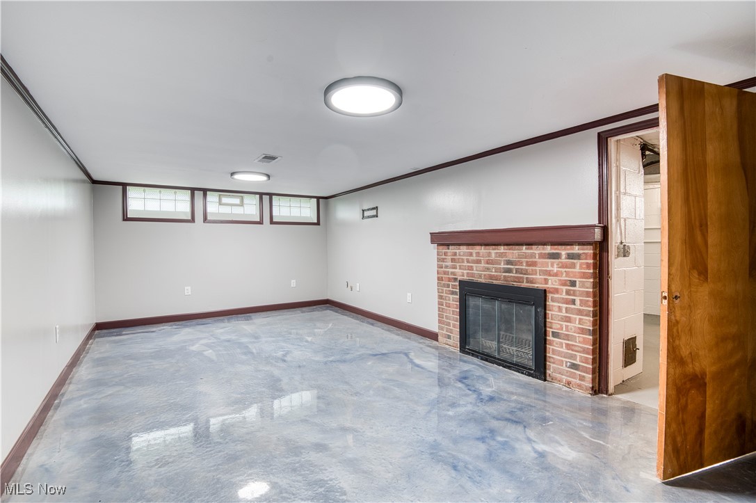 4520 Birchwold Road Cleveland, OH 44121 - Photo 26 of 40 Unfurnished finished side of basement featuring epoxied flooring, crown molding, and a fireplace