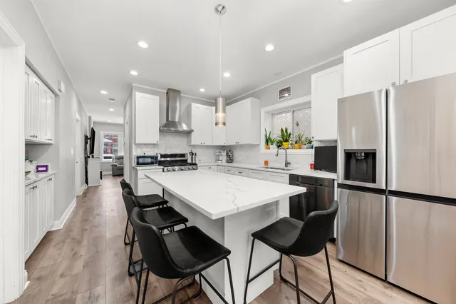 a kitchen with stainless steel appliances a refrigerator a stove a sink a dining table and chairs