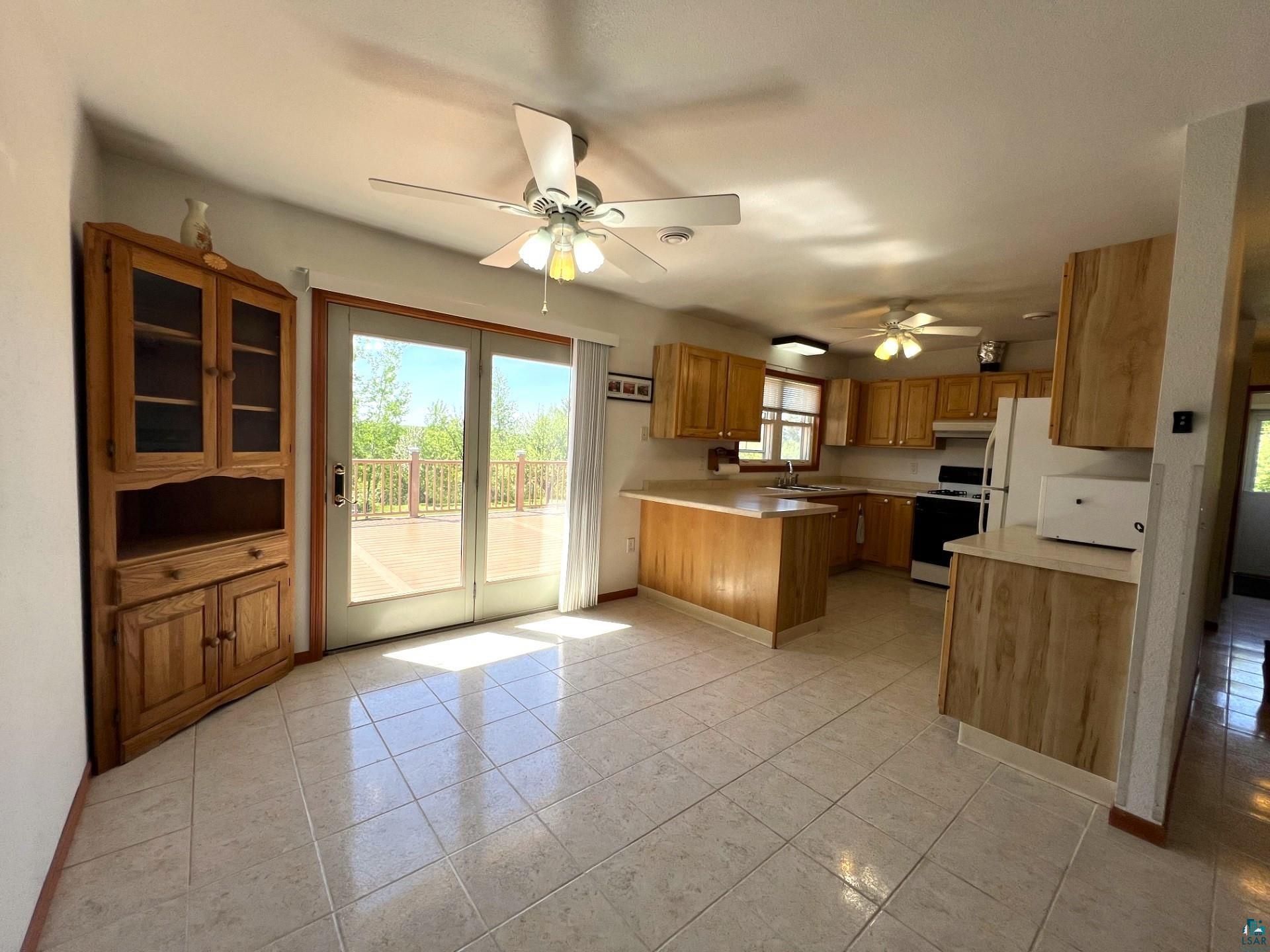 5144 Eagle Lake Road Duluth, MN 55803 - Photo 16 of 47 Kitchen with ceiling fan, kitchen peninsula, light tile flooring, and stove