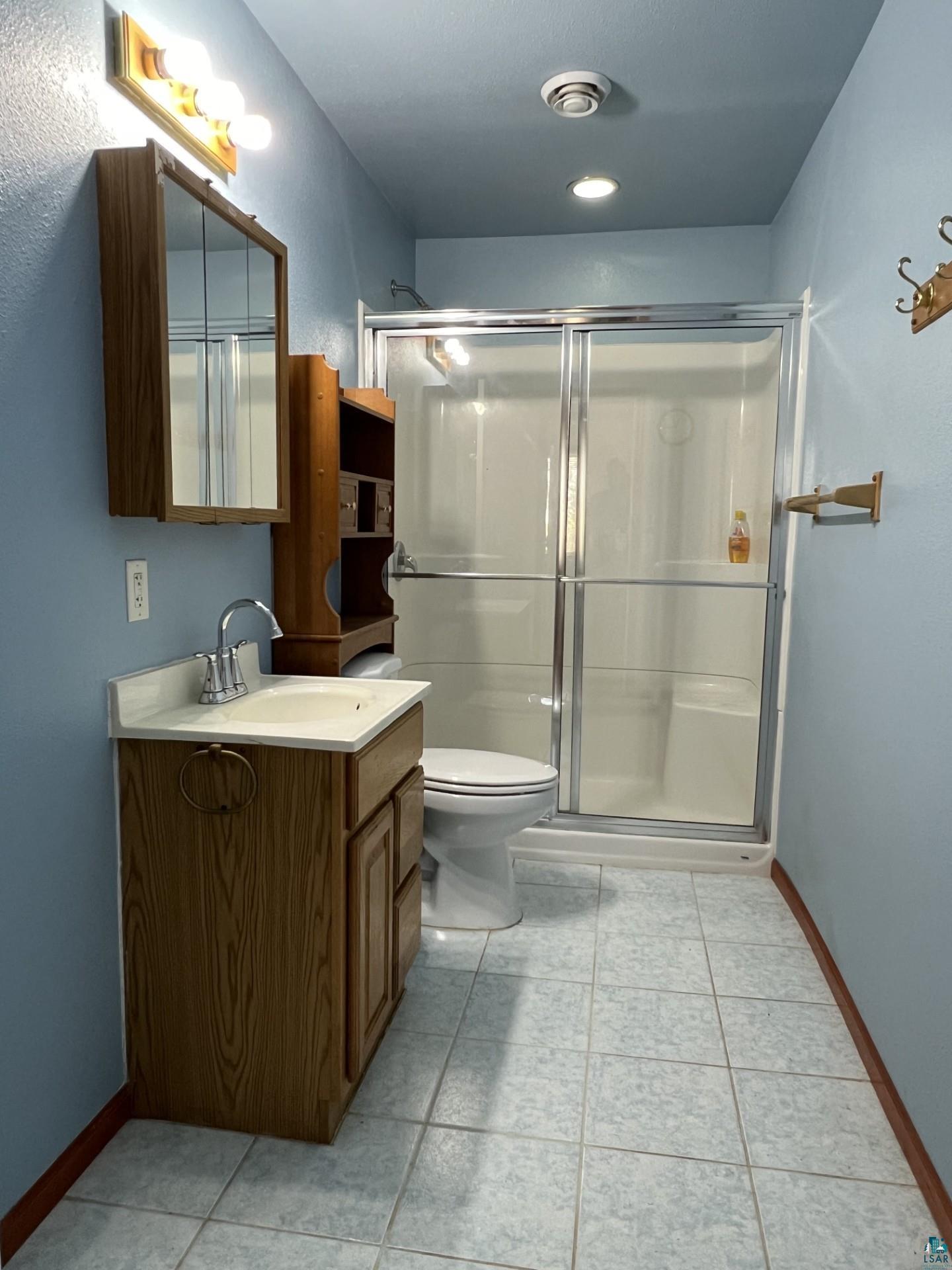 5144 Eagle Lake Road Duluth, MN 55803 - Photo 28 of 47 Bathroom with tile floors, an enclosed shower, toilet, and vanity