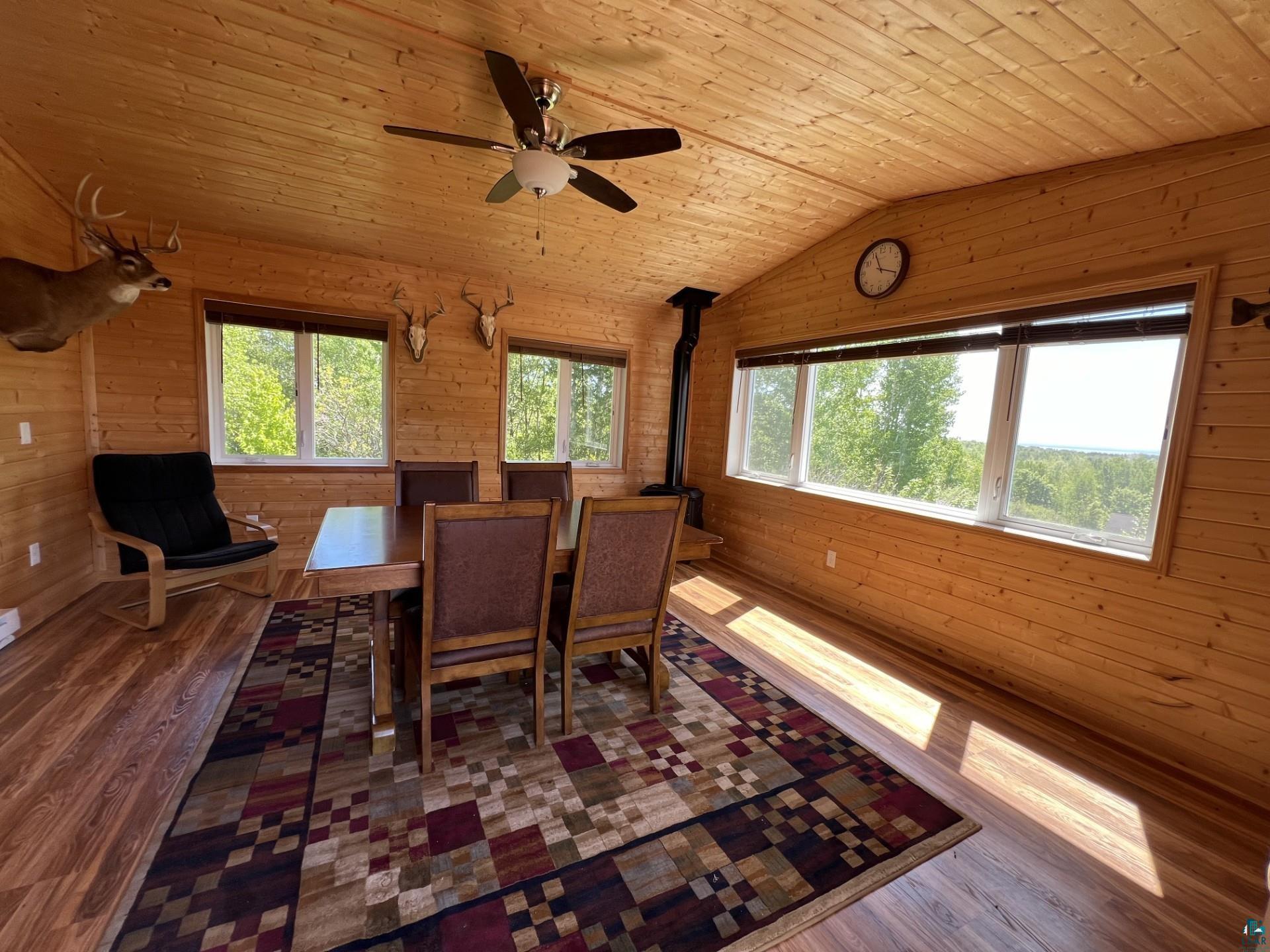 5144 Eagle Lake Road Duluth, MN 55803 - Photo 30 of 47 Dining room with hardwood / wood-style floors, vaulted ceiling, wood ceiling, a wood stove, and wooden walls