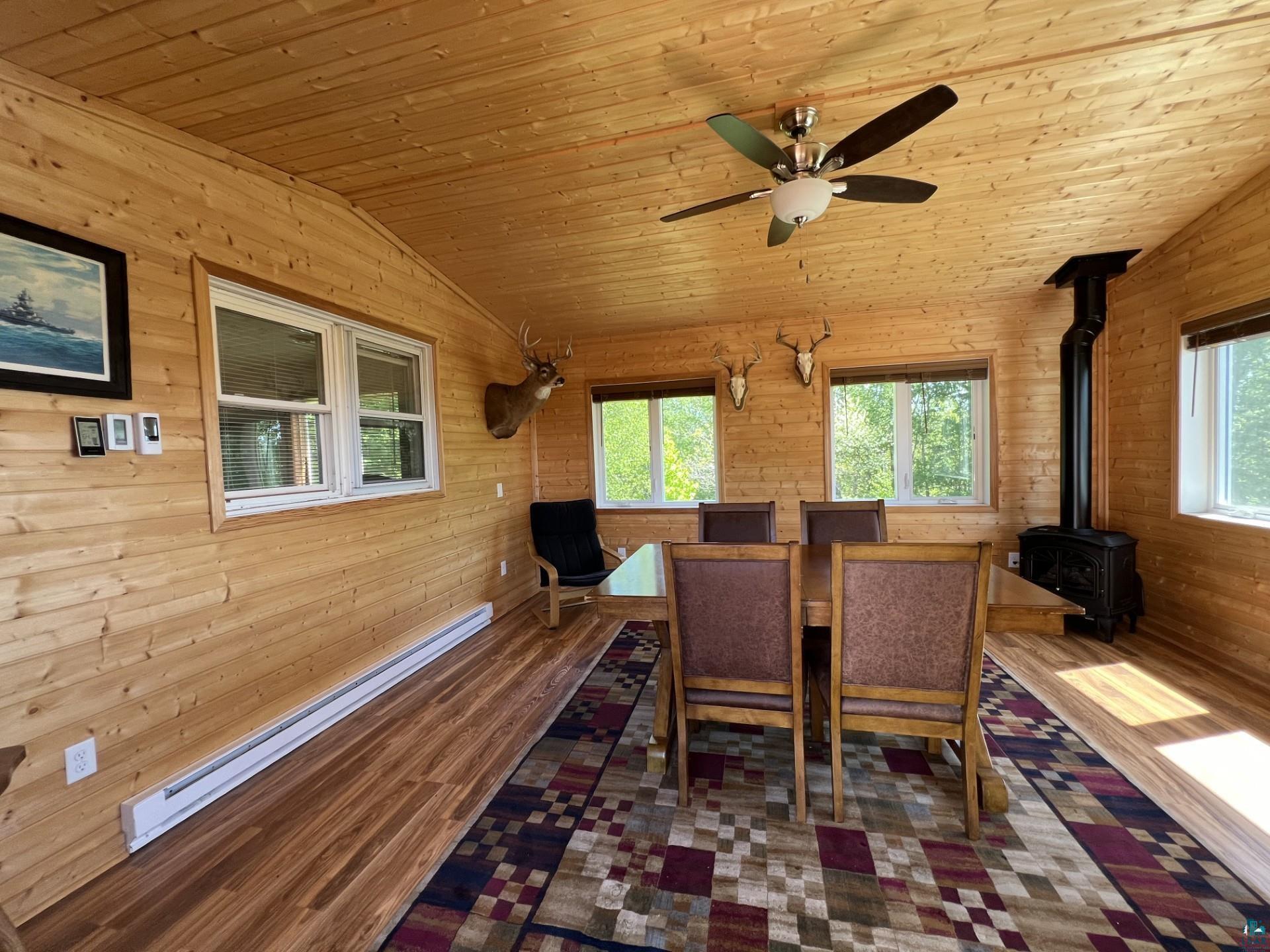 5144 Eagle Lake Road Duluth, MN 55803 - Photo 31 of 47 Dining area with vaulted ceiling, a healthy amount of sunlight, a wood stove, and wood ceiling