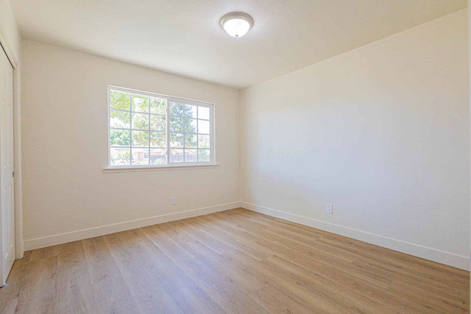 17925 Rodeo Drive Madera, CA 93638 - Photo 16 of 26 an empty room with wooden floor and windows