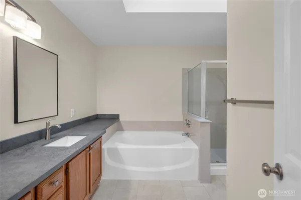 a bathroom with a granite countertop sink and mirror with bathtub