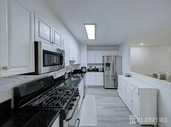 a kitchen with stainless steel appliances a refrigerator oven a sink a stove and white cabinets