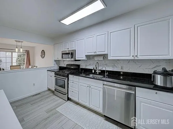 a kitchen with granite countertop white cabinets and stainless steel appliances