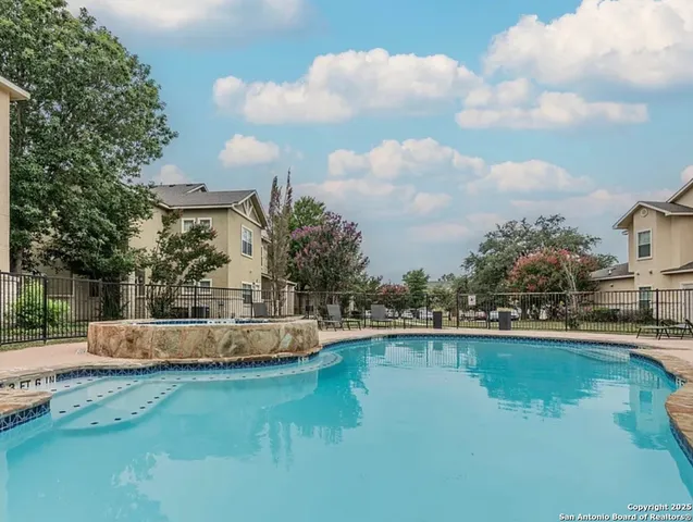 a view of a swimming pool with a fountain and large trees