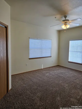 an empty room with windows and fan