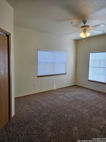 an empty room with windows and fan