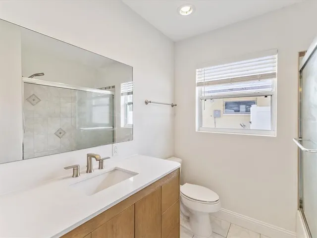 a bathroom with a granite countertop sink toilet and mirror