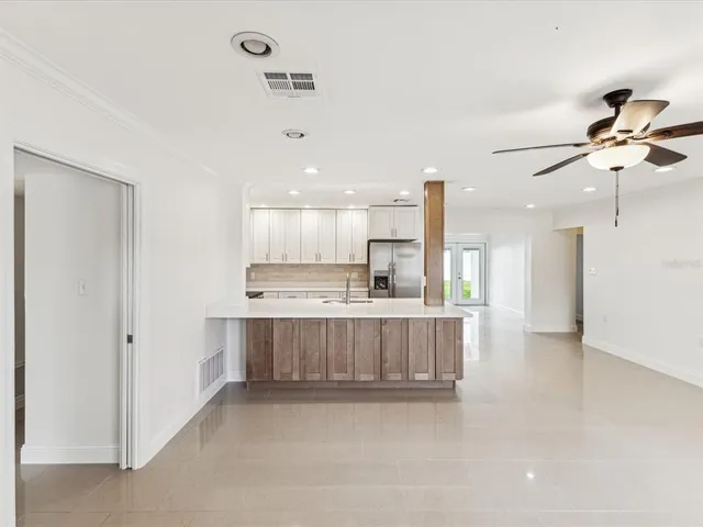 a view of kitchen with kitchen island stainless steel appliances wooden floor cabinets and a window