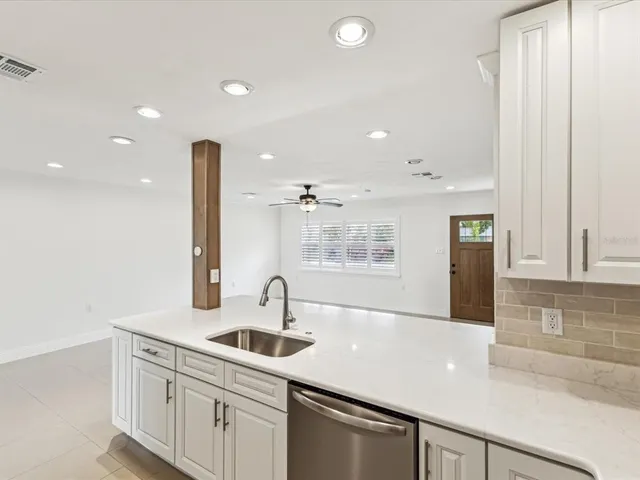a kitchen with a sink dishwasher and white cabinets with wooden floor