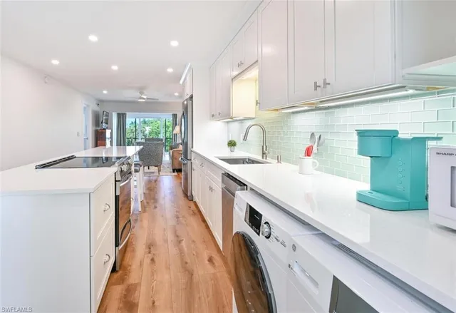 a kitchen with kitchen island granite countertop a sink a counter top space stainless steel appliances and cabinets