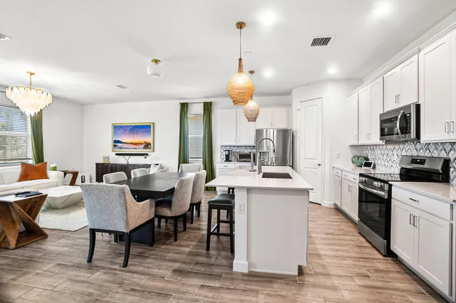 a open kitchen with stainless steel appliances granite countertop a stove a refrigerator a kitchen island a dining table and chairs