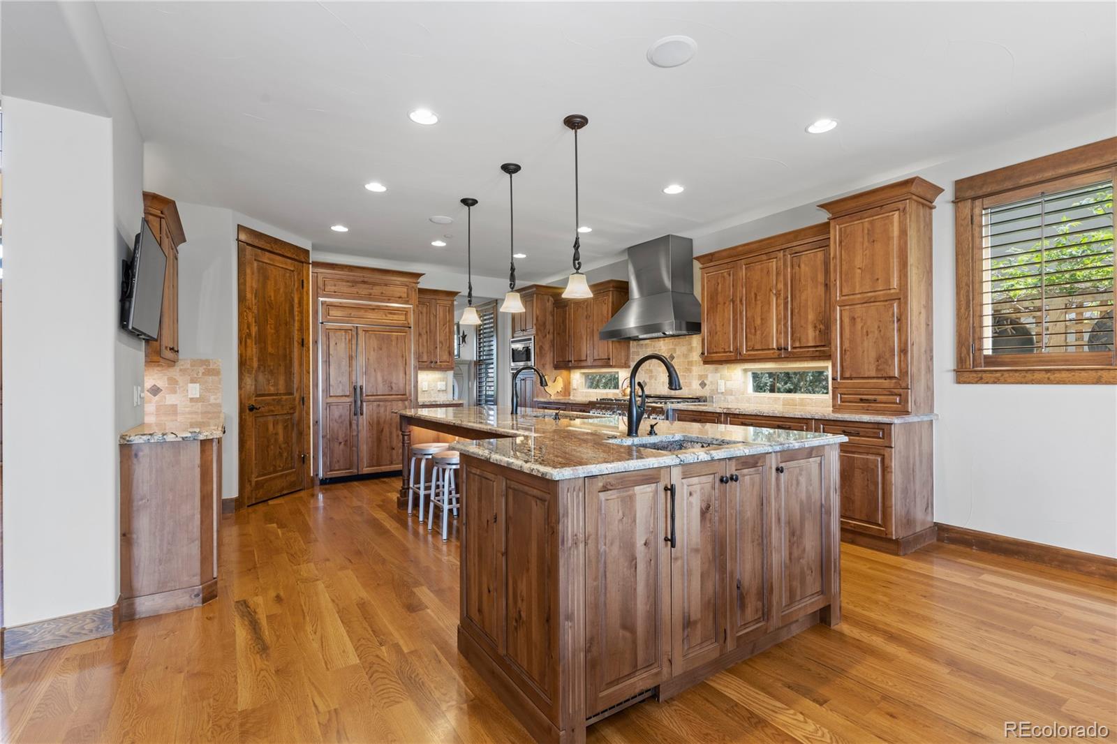1291 Buffalo Ridge Road Castle Pines, CO 80108 - Photo 9 of 39 a kitchen with stainless steel appliances granite countertop a sink a stove a refrigerator cabinets and wooden floor