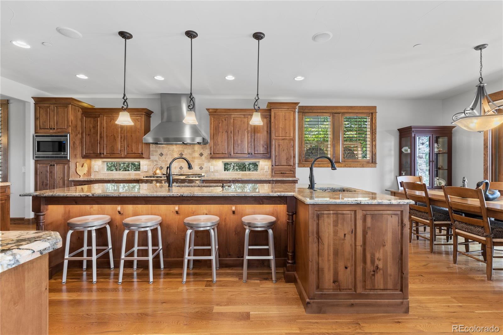 1291 Buffalo Ridge Road Castle Pines, CO 80108 - Photo 10 of 39 a kitchen with stainless steel appliances granite countertop a stove top oven a sink a dining table and chairs with wooden floor