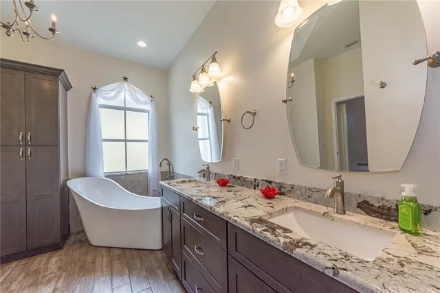 a bathroom with a granite countertop bathtub a sink and a large mirror