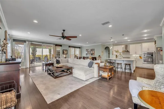 a living room with furniture kitchen view and a large window