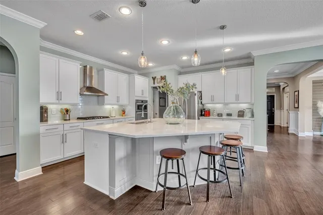 a kitchen with kitchen island granite countertop wooden floors and white cabinets