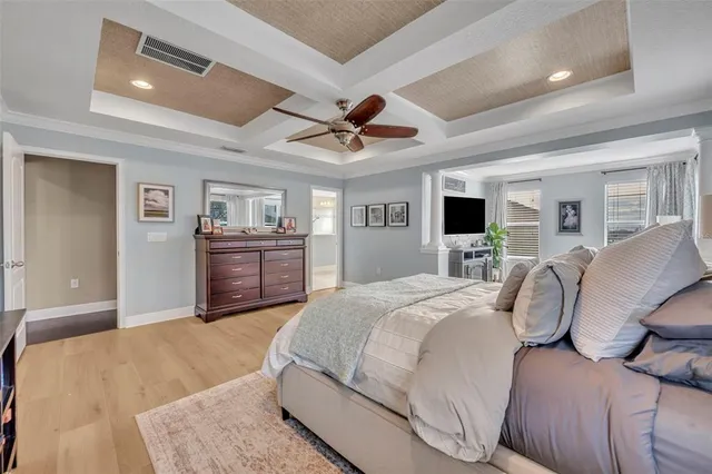 a spacious bedroom with a bed a dresser and a chandelier