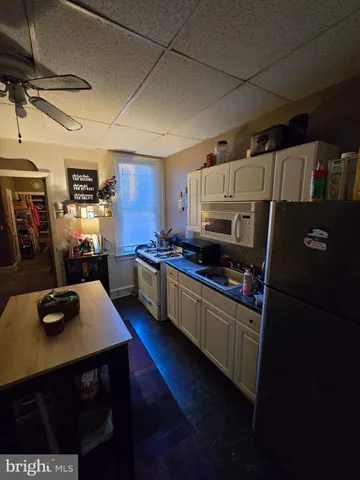 a kitchen with stainless steel appliances granite countertop a refrigerator a sink dishwasher a stove and white countertops with wooden floor