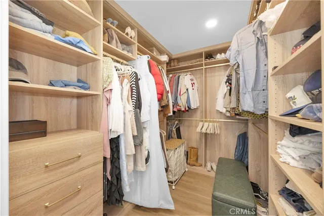 a view of walk in closet with clothes and shoes